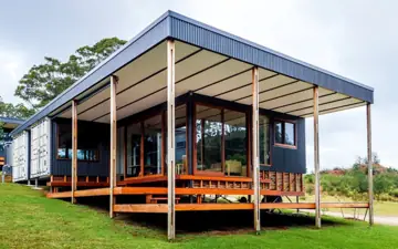 Containerhaus mit breiter überdachter Terrasse und Holzdeck
