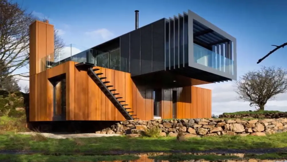 Offset container home with an outdoor staircase beneath a cantilevered upper floor