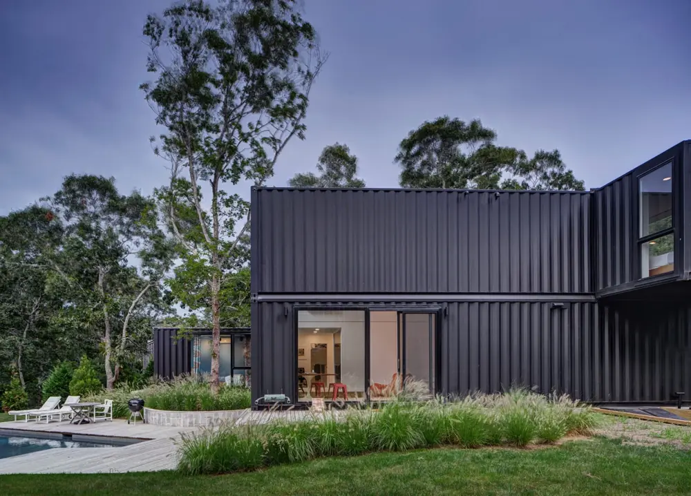Dark stacked living containers with a narrow upper floor in a garden