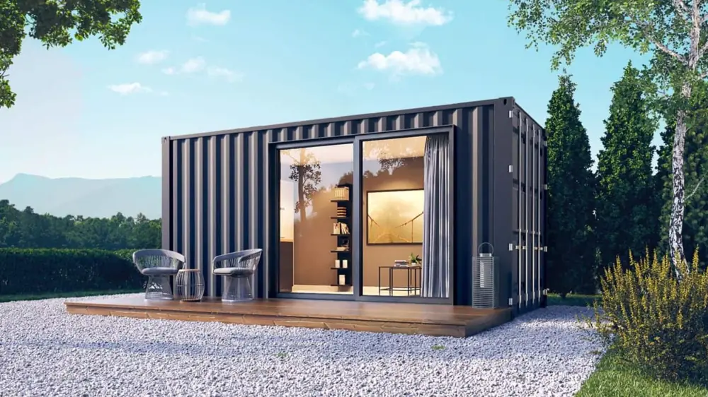 Kleiner dunkler Wohncontainer mit Holzdeck, zwei Stühlen und geöffnetem Eingang