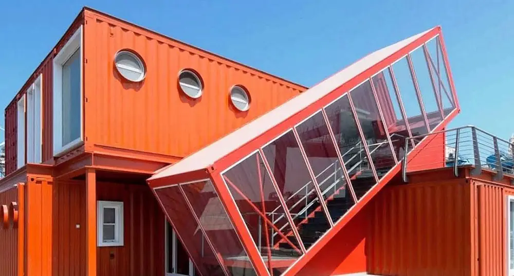 Orange container building with an angled projecting glazed room module
