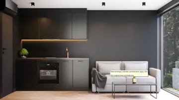 Kompakte dunkle Küchenzeile mit Backofen und Kühlschrank neben einem grauen Sofa