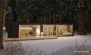Wohnmodul mit langer Glasfront und beleuchtetem Innenraum im Winterwald