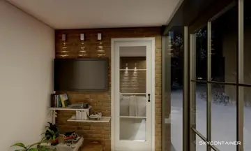 Wohncontainer-Innenraum mit Fernseher an einer Backsteinwand neben der Küche