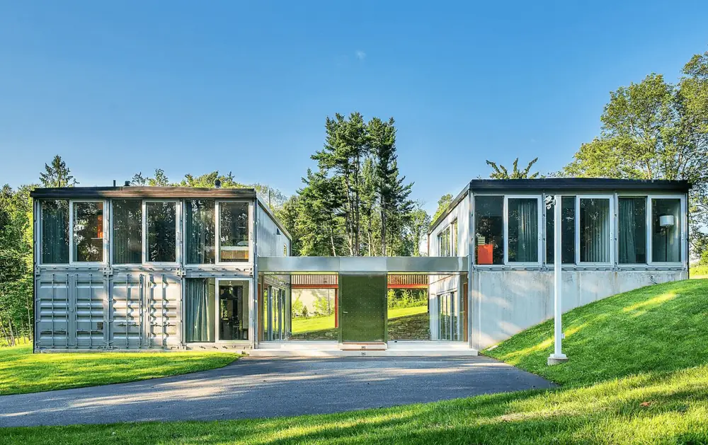 Two light container garden houses with glazed ends beside a driveway