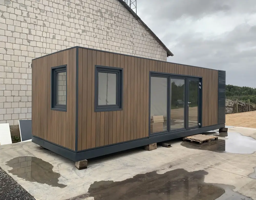 Timber-clad container extension beside a light masonry house wall