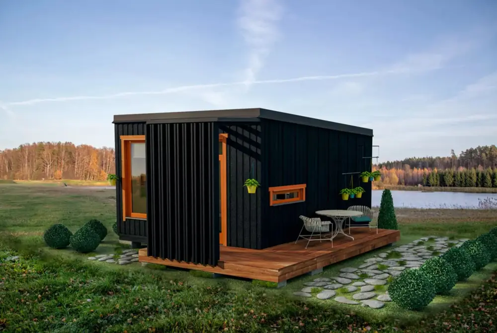 Black container bungalow with a small timber terrace and planters beside water