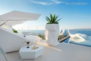Weiße Terrassenmöbel und Pflanzgefäße vor Meerblick