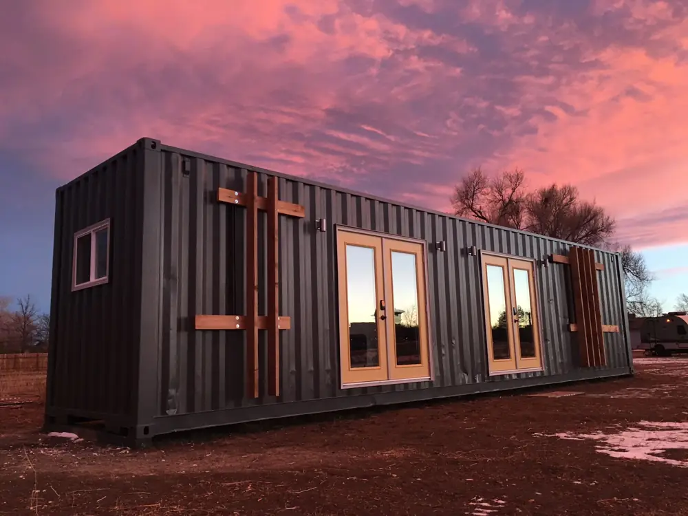 Dark container home under a red evening sky