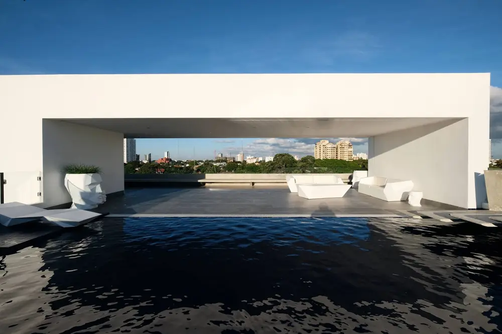 Weiße Lounge-Sitzgruppe unter einem flachen Terrassendach neben dem Pool