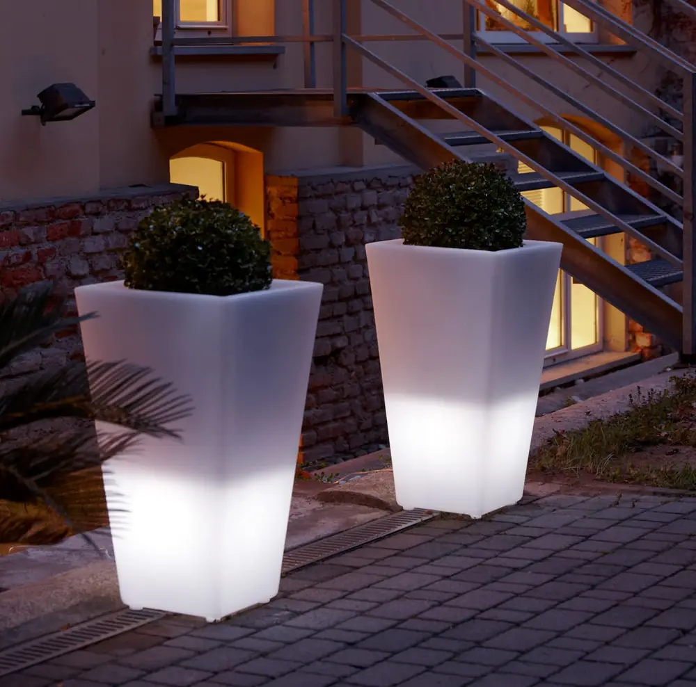 Beleuchtete weiße Pflanzgefäße auf einer Terrasse