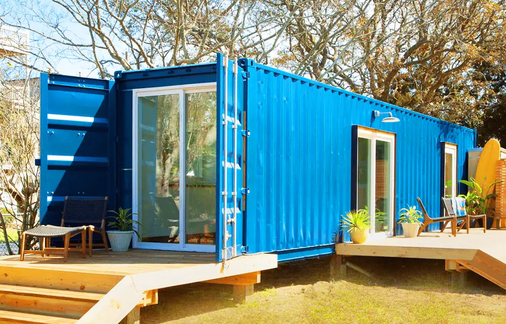 Turquoise container in a garden with corner glazing and timber steps