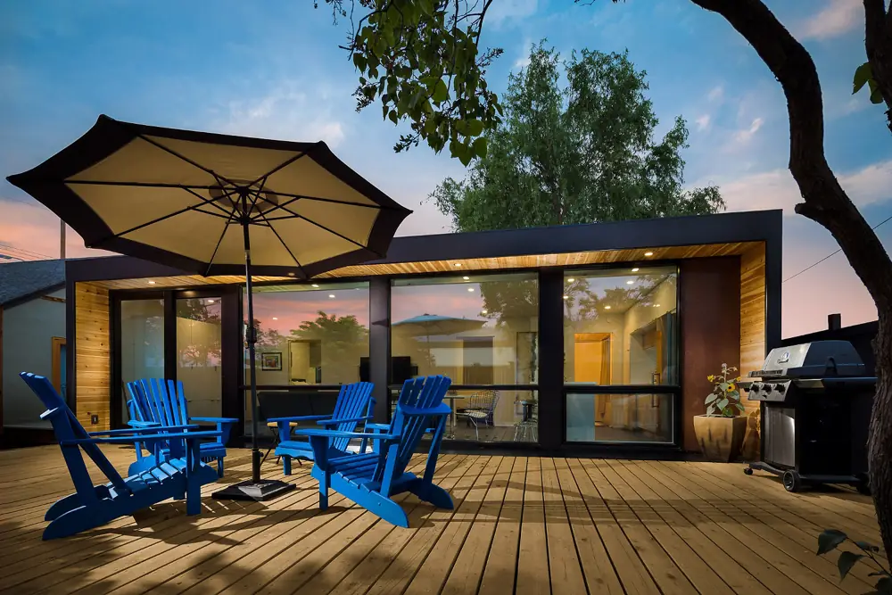 Container garden house with wide glazing and blue terrace chairs