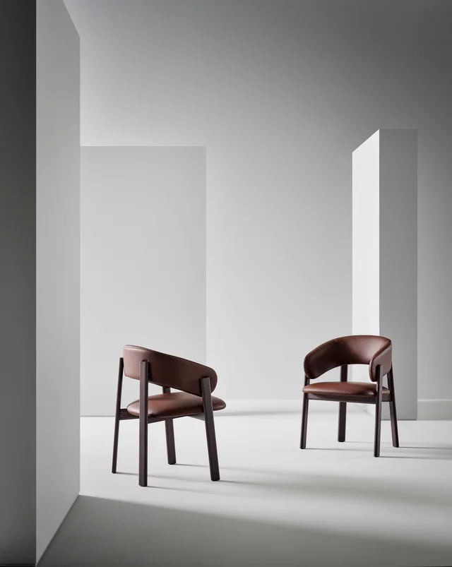 Bonaldo Alpha: Brown upholstered chair with a wrapping back and dark wooden frame · View 1