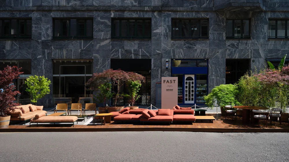 Fast Via Durini 2026: Street-side terrace with warm upholstery, plants and different table surfaces · View 1