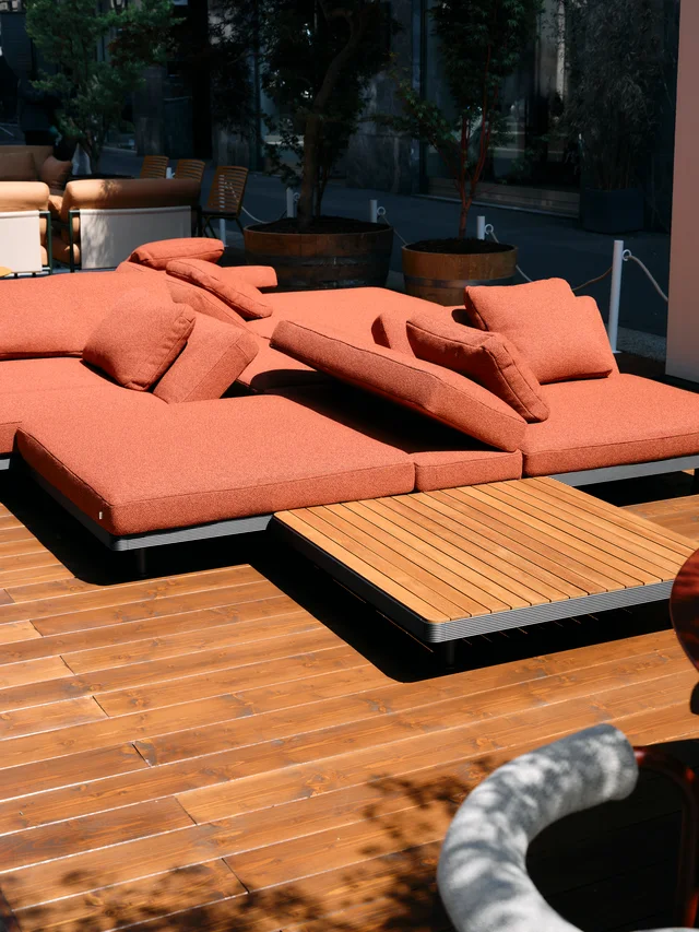 Fast Via Durini 2026: Street-side terrace with warm upholstery, plants and different table surfaces · View 6