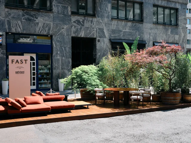 Fast Via Durini 2026: Street-side terrace with warm upholstery, plants and different table surfaces · View 12