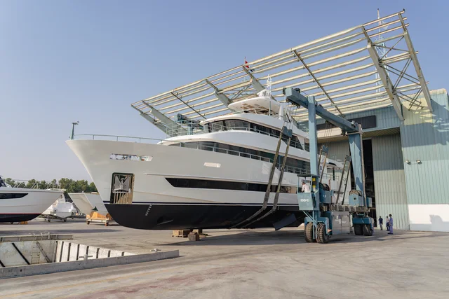 Gulf Craft Nomad 101: schräge Bugansicht der weißen Yacht im Hebesystem vor der Werfthalle