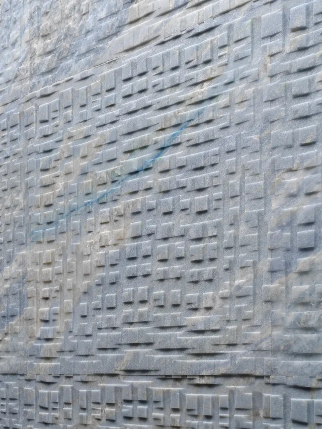 Lithos Design Polis Calcite Blu: Blau-weiß nuancierte reliefierte Steinwand und helle Badraumansichten · Ansicht 2