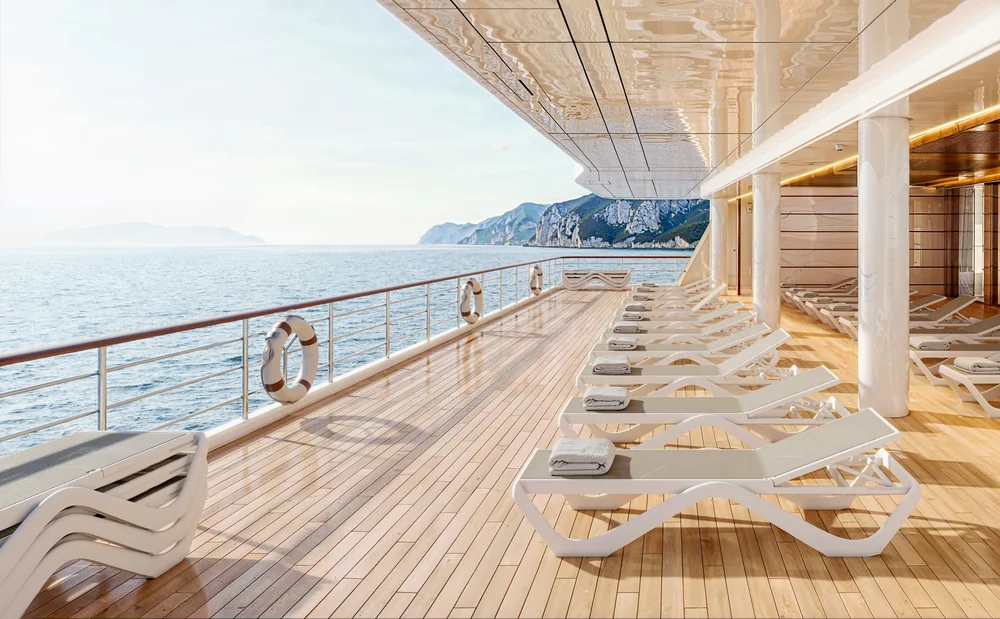 VONDOM LOVE: weiße Liegen auf einem langen Holzdeck mit Geländer und Meerblick