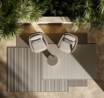 VONDOM outdoor rugs: overhead view of a striped rectangular rug with two armchairs and a small round table