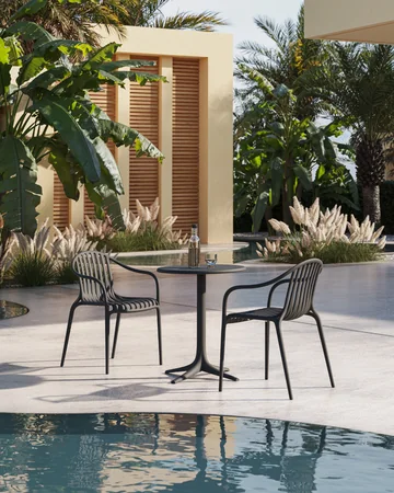 VONDOM PALM: dunkle Stühle an einem runden Tisch vor Palmen und einer Wasserfläche