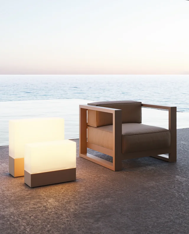 VONDOM POSIDONIA: heller Lounge-Sessel neben zwei leuchtenden Quadern vor dem Meer