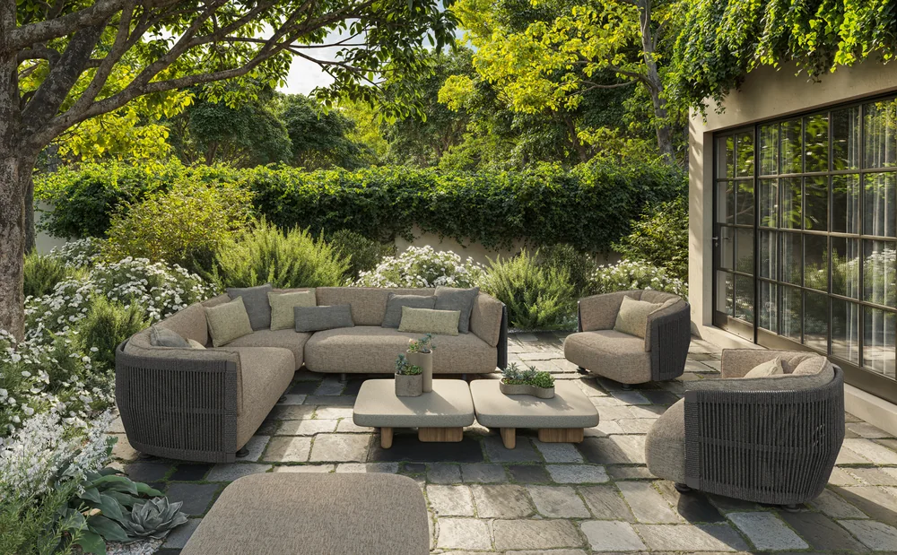 VONDOM SERRA: dunkle und helle Lounge-Möbel um niedrige Tische im grünen Garten