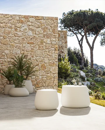 VONDOM STONE: pale rounded planters and stools beside a stone wall