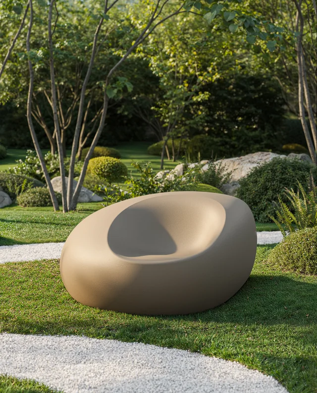 VONDOM STONE: einzelner gerundeter Sessel schräg auf einer Gartenwiese